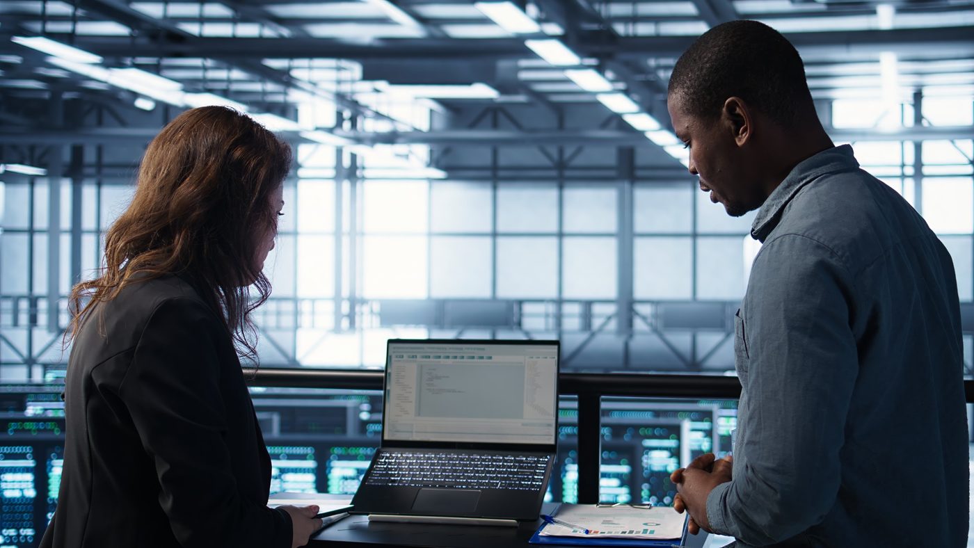 Deux personnes examinant du code sur un ordinateur portable.