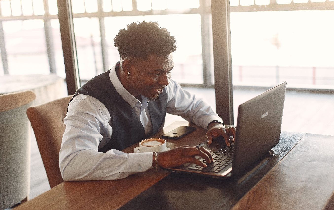 Entrepreneur africain travaillant sur un ordinateur dans un café.