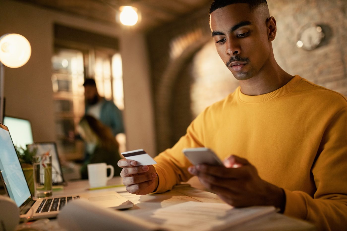 Client réalisant un paiement en ligne avec sa carte et son téléphone.