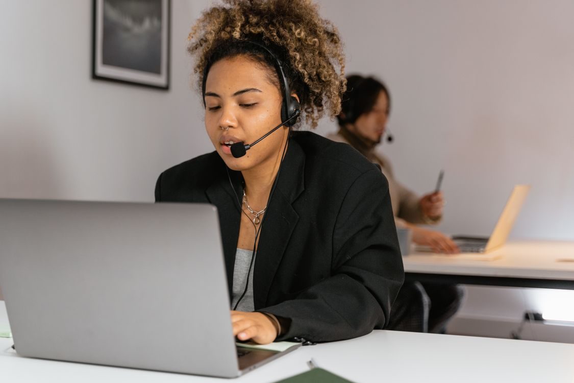 Professionnelle africaine travaillant dans un service de relation client avec casque et ordinateur.
